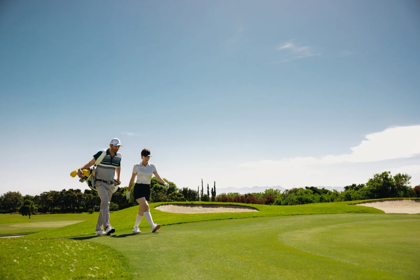 Two golfers walking across a green