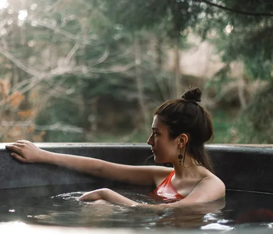 Woman relaxing in an outdoor pool surrounded by forest