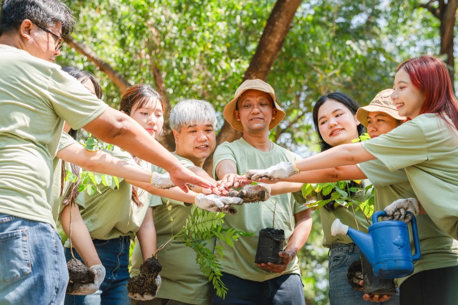 Volunteers of all ages stacking hands together in a forest clearing